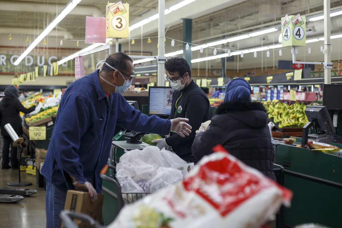 Two customers place their groceries in their cart while checking out at Greenland Market on the first day of Ramadan on April 23, 2020 in Dearborn Heights, Michigan. Due to the social distancing guidelines being enforced to combat the spread of the coronavirus (COVID-19) the Muslim holy month of Ramadan is going to be observed much differently this year amidst the pandemic.