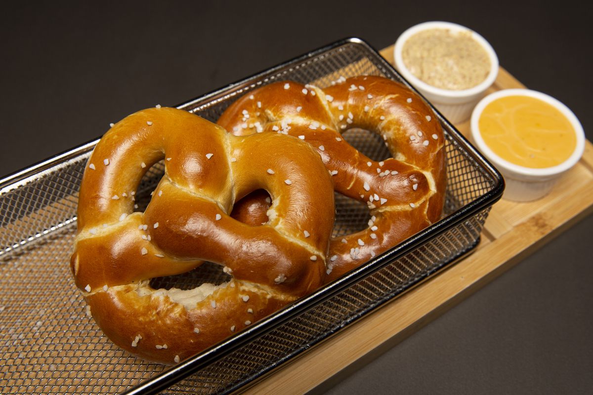 Two large, soft pretzels in a wire basket.