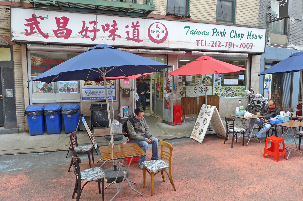 A storefront with several umbrella tables in front.