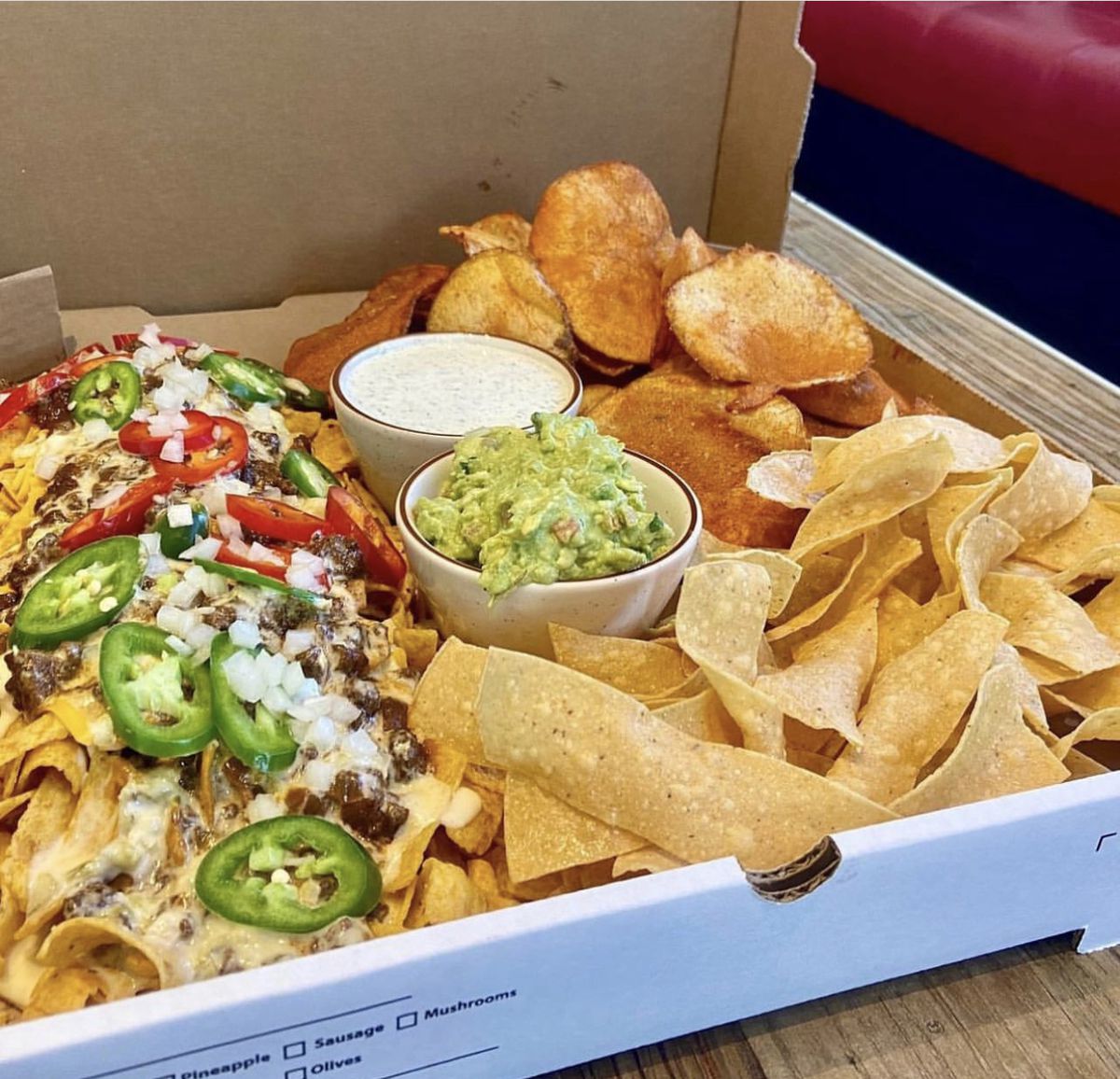 State Fare Kitchen & Bar’s party box, which includes tortilla chips with salsa, seasoned chips and pickle dip, and a Frito pie loaded with jalapenos, onions, peppers, and cheese.