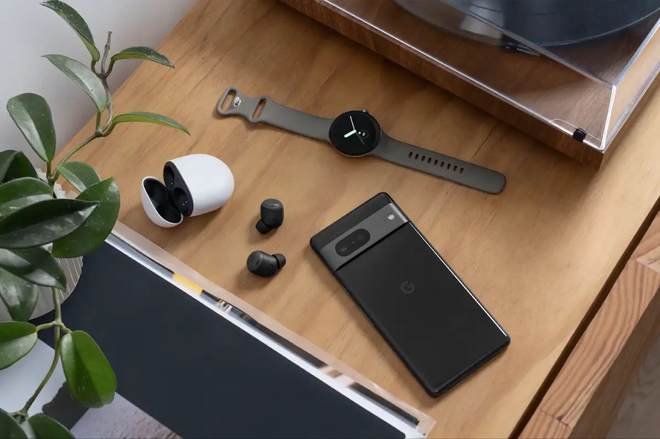 A photo of the Pixel 7, Pixel Watch, and a set of Pixel Buds Pro on a wooden surface.