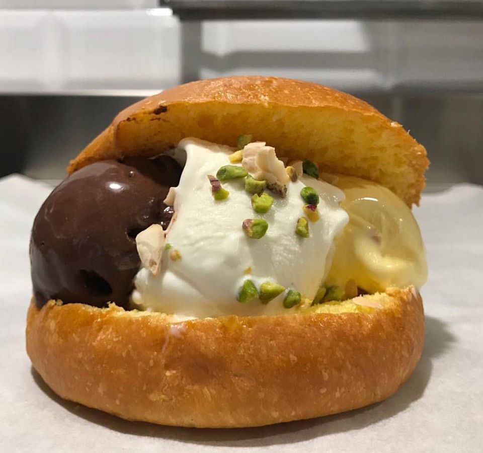 An ice cream sandwich stuffed with three kinds of ice cream, including glossy chocolate and one dotted with chopped pistachios