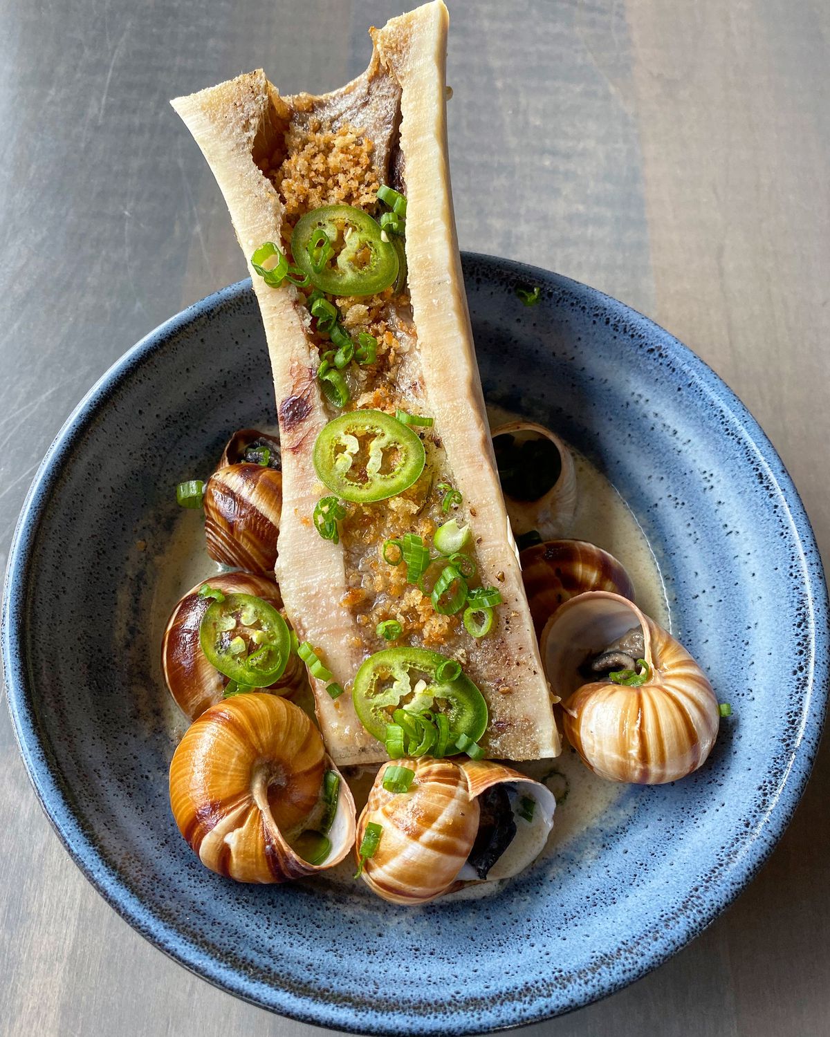 A blue dish of snails and bone marrow
