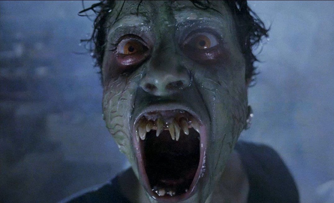 A monster with a green face bares his crooked teeth in Demons 2.