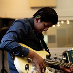 Eli Sackett, a student at the Utah Schools for the Deaf and the Blind, plays guitar in a studio at Spy Hop in Salt Lake City on Friday, Feb. 15, 2019. Sackett is visually impaired and wears two cochlear implants to help him hear.