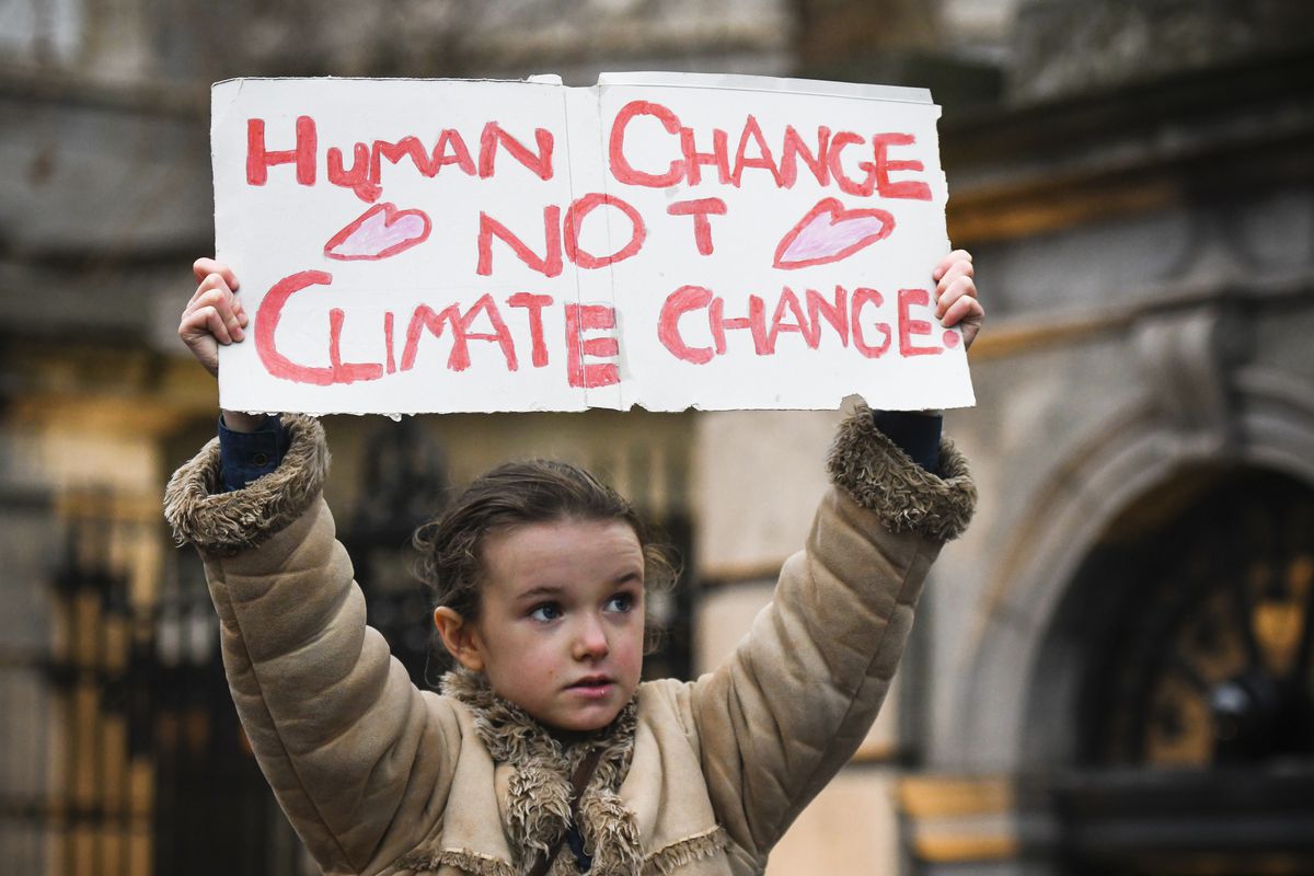 Young activist holds ‘Human Change Not Climate Change’ sign during a rally for climate in Dublin, Ireland.