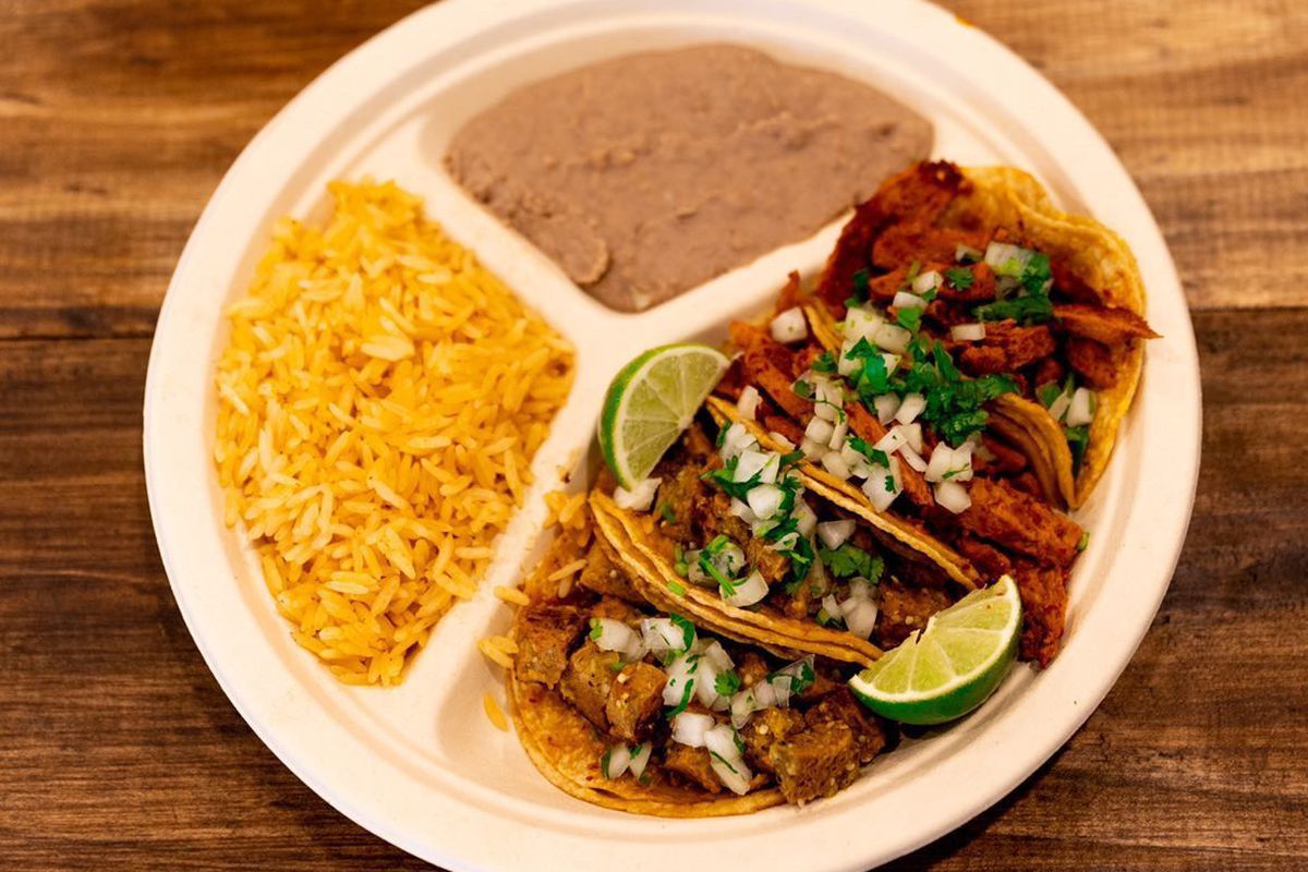 A plate of several tacos, rice, and refried beans.