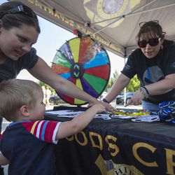 Hailey Maloney, left, helps her son Collin, 2, pick out a prize with the assistance of volunteer Elisa Braghin during the National Night Out event at Hogan Park in Woods Cross on Monday, July 31, 2017. Woods Cross held its event the day before the national night of celebration.