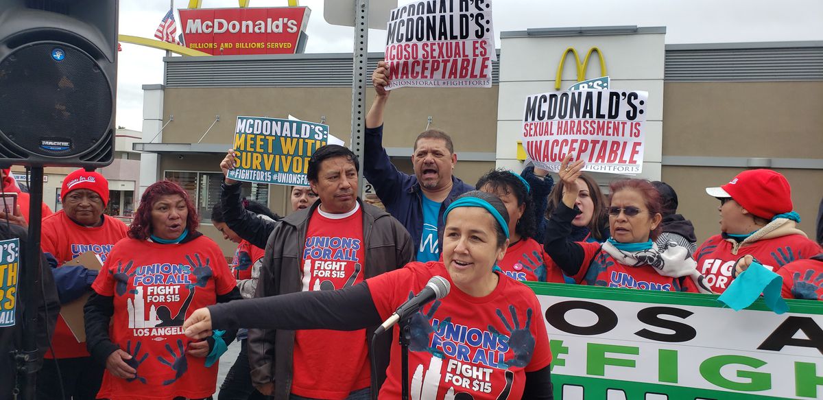 Protesters outside a McDonald’s wear shirts that read “Unions for all, fight for $15” and carry signs that read, “McDonald’s: Sexual harassment is unacceptable” and “McDonald’s: Meet with survivors>”