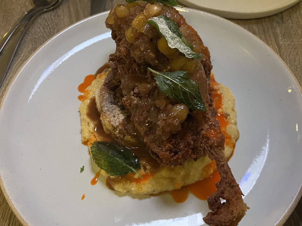 A plate of grits topped with a fried pigeon.
