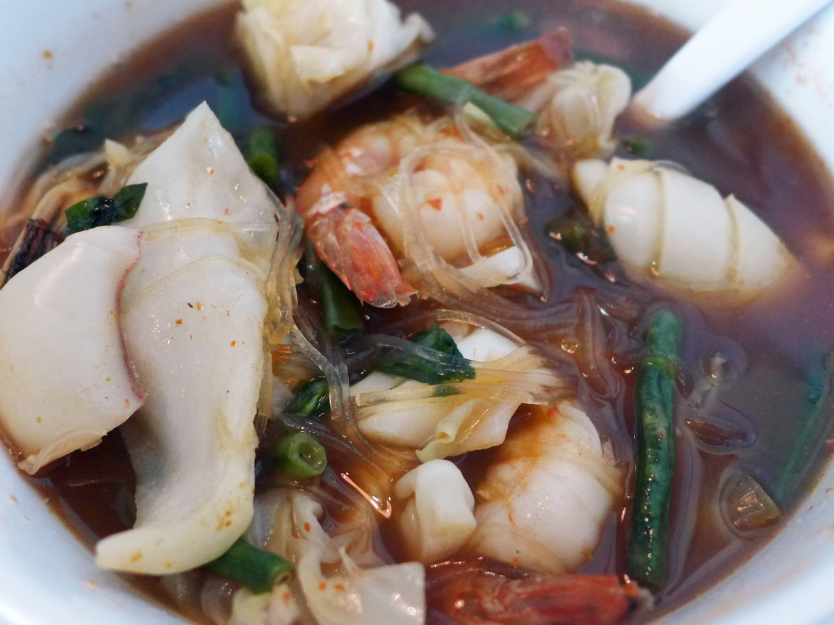 Thai seafood soup with shrimp and squid in a very dark broth.