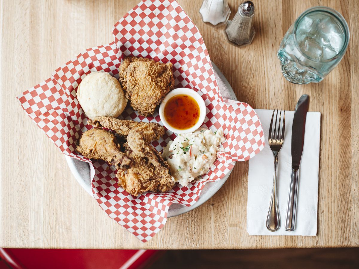 An overhead shot of fried chicken resting on a plate that is covered with a red and white checkered sheet of wax paper 