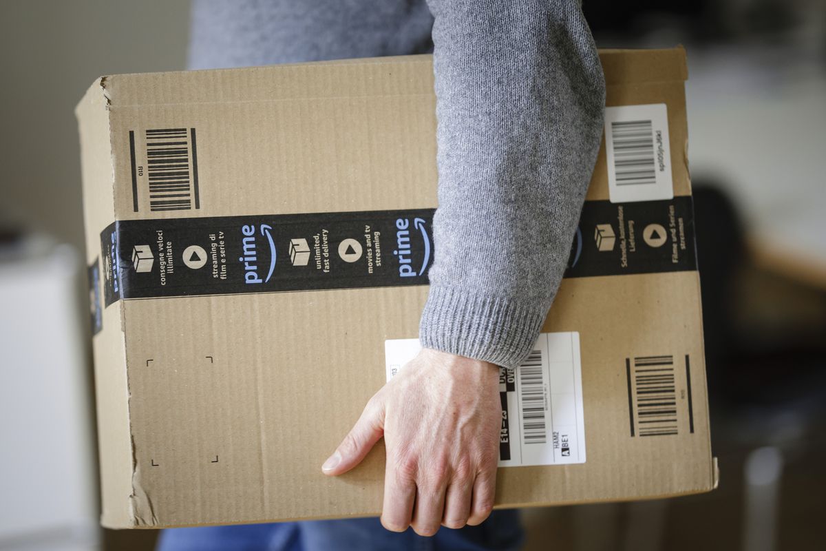 A person carries an Amazon Prime-branded package under their arm.