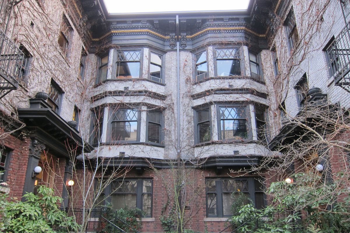 An apartment building with bay windows, viewed from inside a courtyard.