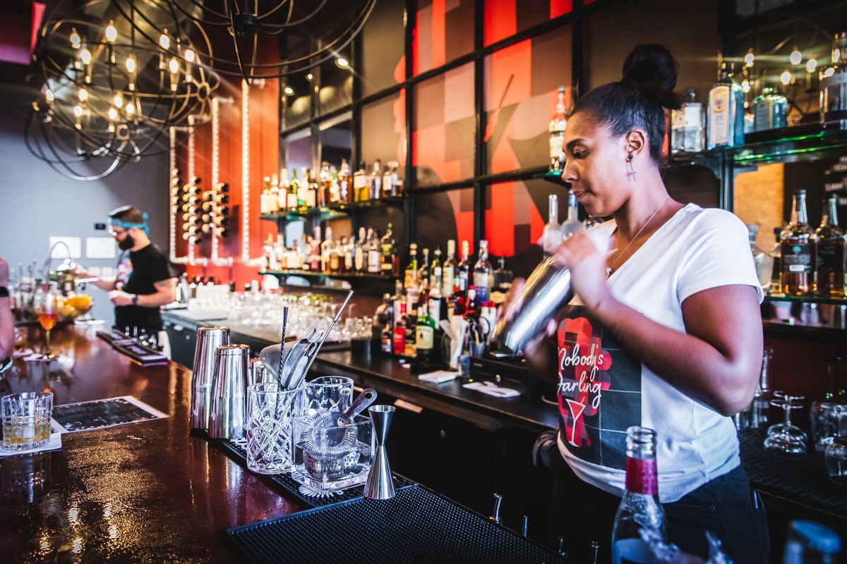 A bartender shakes a cocktail behind the bar.