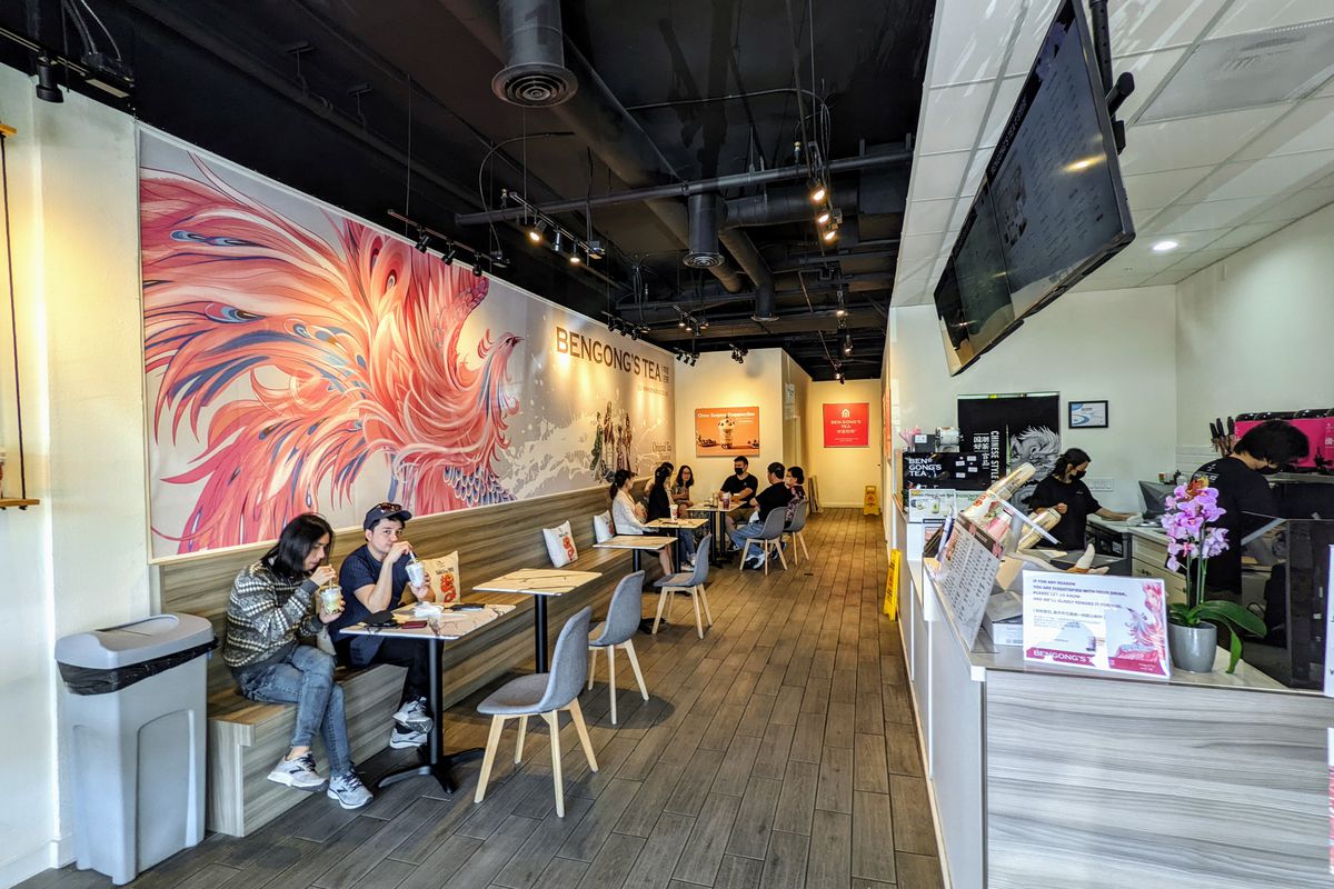 Interior view of BenGong’s boba tea shop in Arcadia: seated customers drinking different boba teas from a wooden bench attached to the walls beneath painted murals.