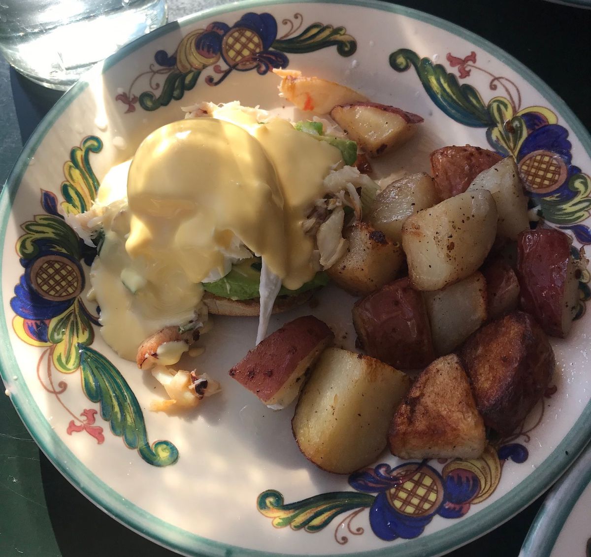 A flowered plate with eggs Benedict covered in hollandaise.