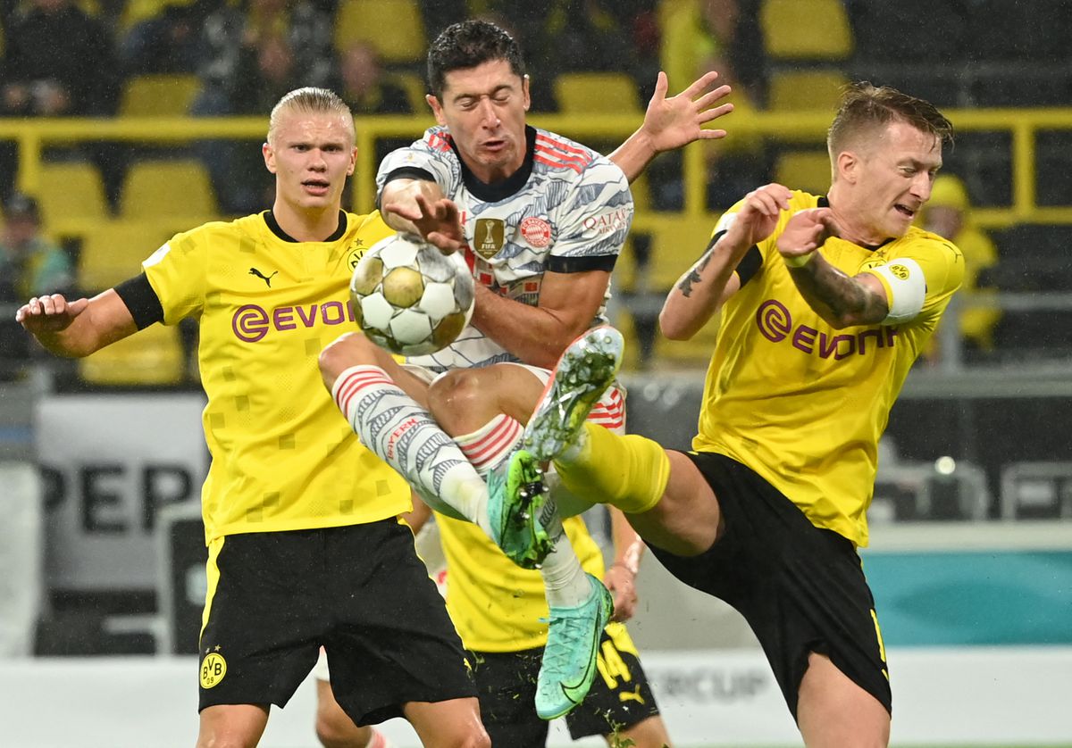 Lewandowski, in a Bayern shirt, vies for the ball, sandwiched between Erling Haaland and Marco Reus