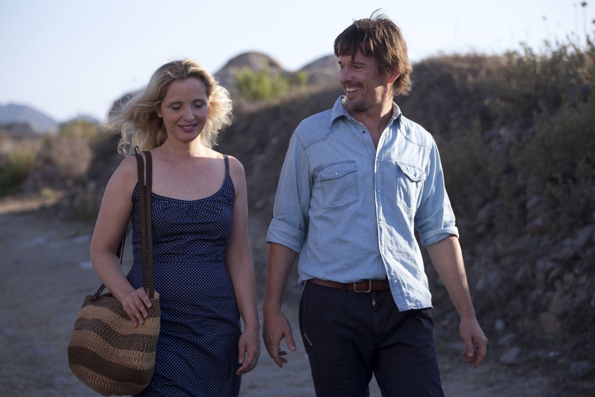 Celine (Julie Delpy) and Jesse (Ethan Hawke) walking alongside one another and smiling in Before Midnight.