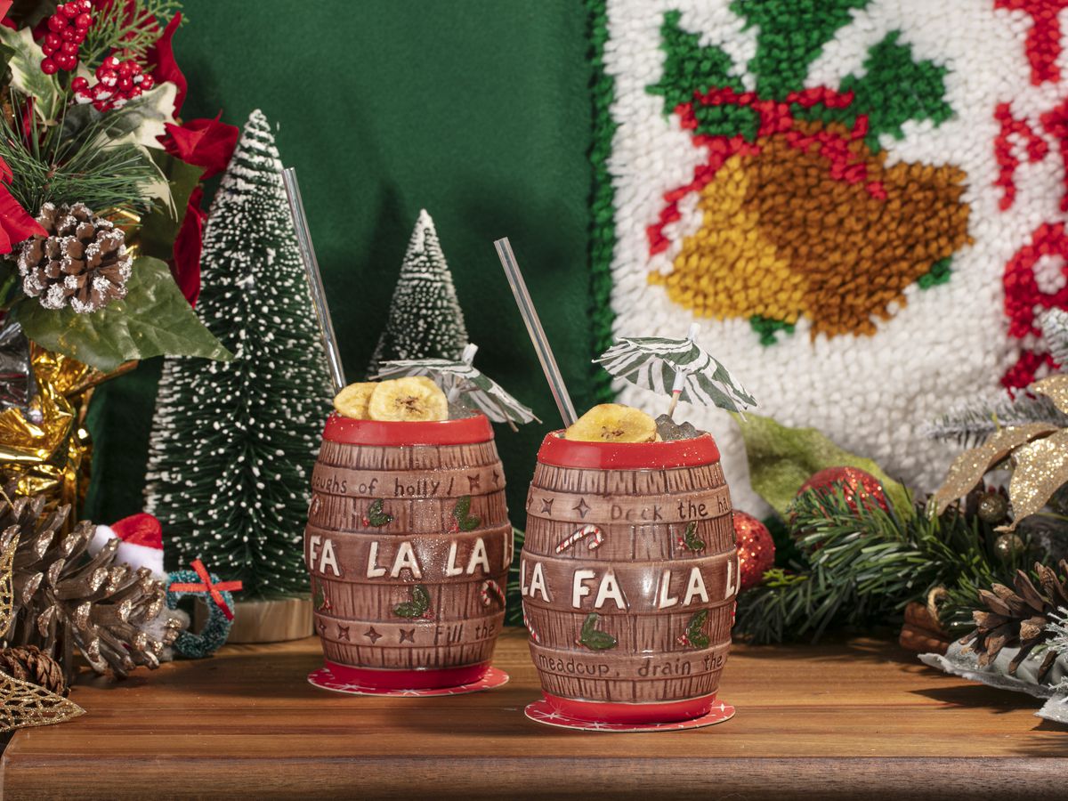 Two barrel-shaped mugs filled with cocktails sit against a festive background.