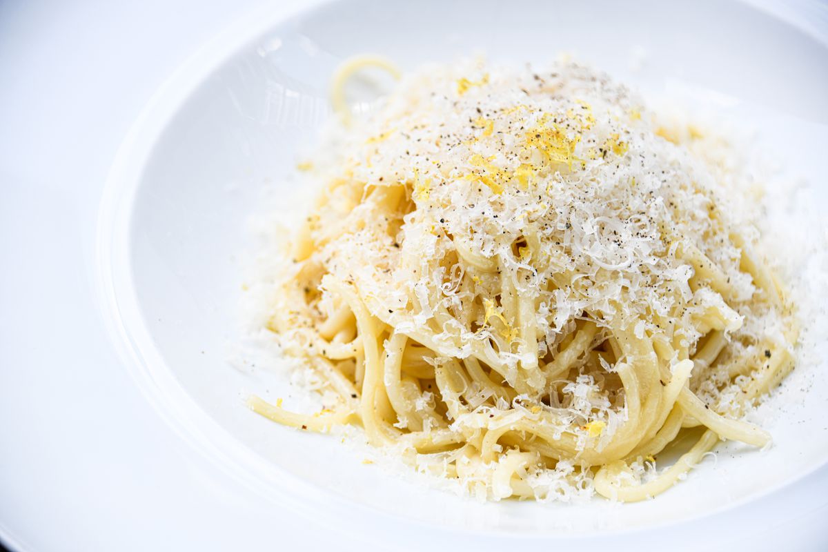 A white pasta bowl filled with Caco e pepe sprinkled with fresh shaved parmesan cheese from Tre Vele in Sandy Springs, GA