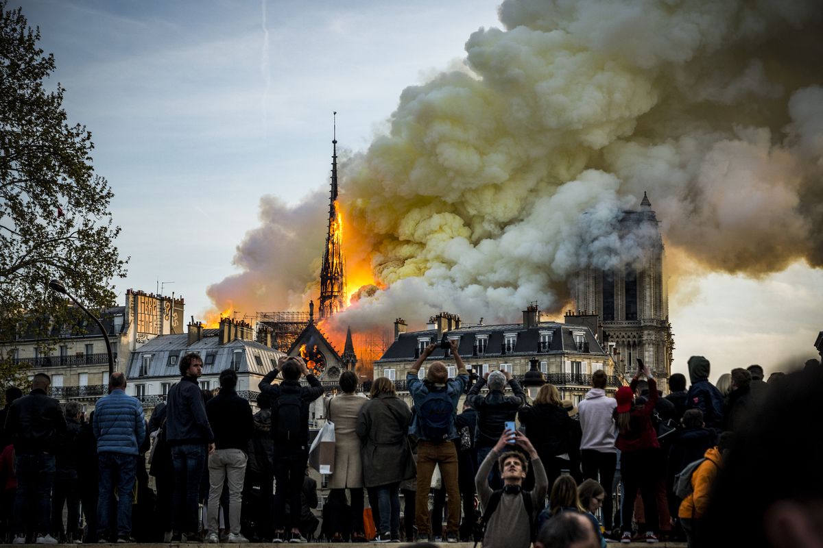 People watch the landmark Notre Dame Cathedral burning in central Paris on April 15, 2019.