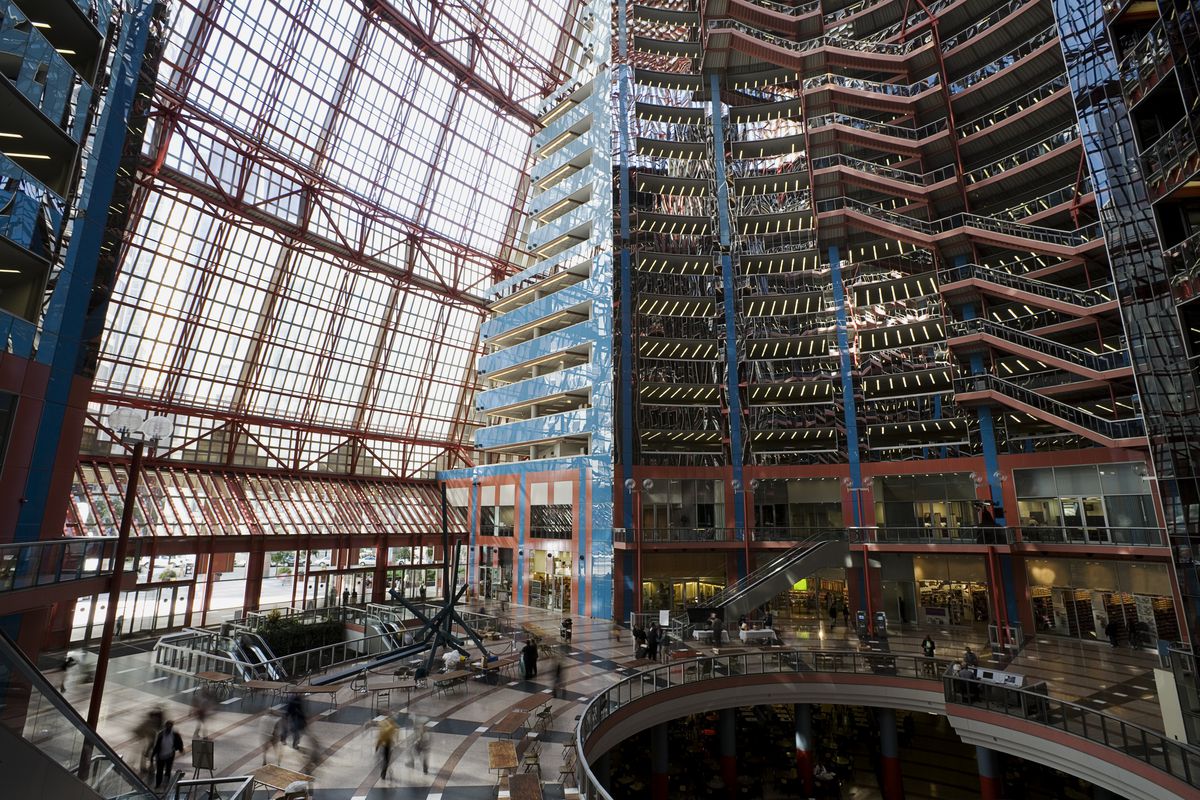 A ciculaur, glass-enclosed atrium with a round lobby and sunken food court. The upper floors are ringed in office space and accessed by a glass elevator. 