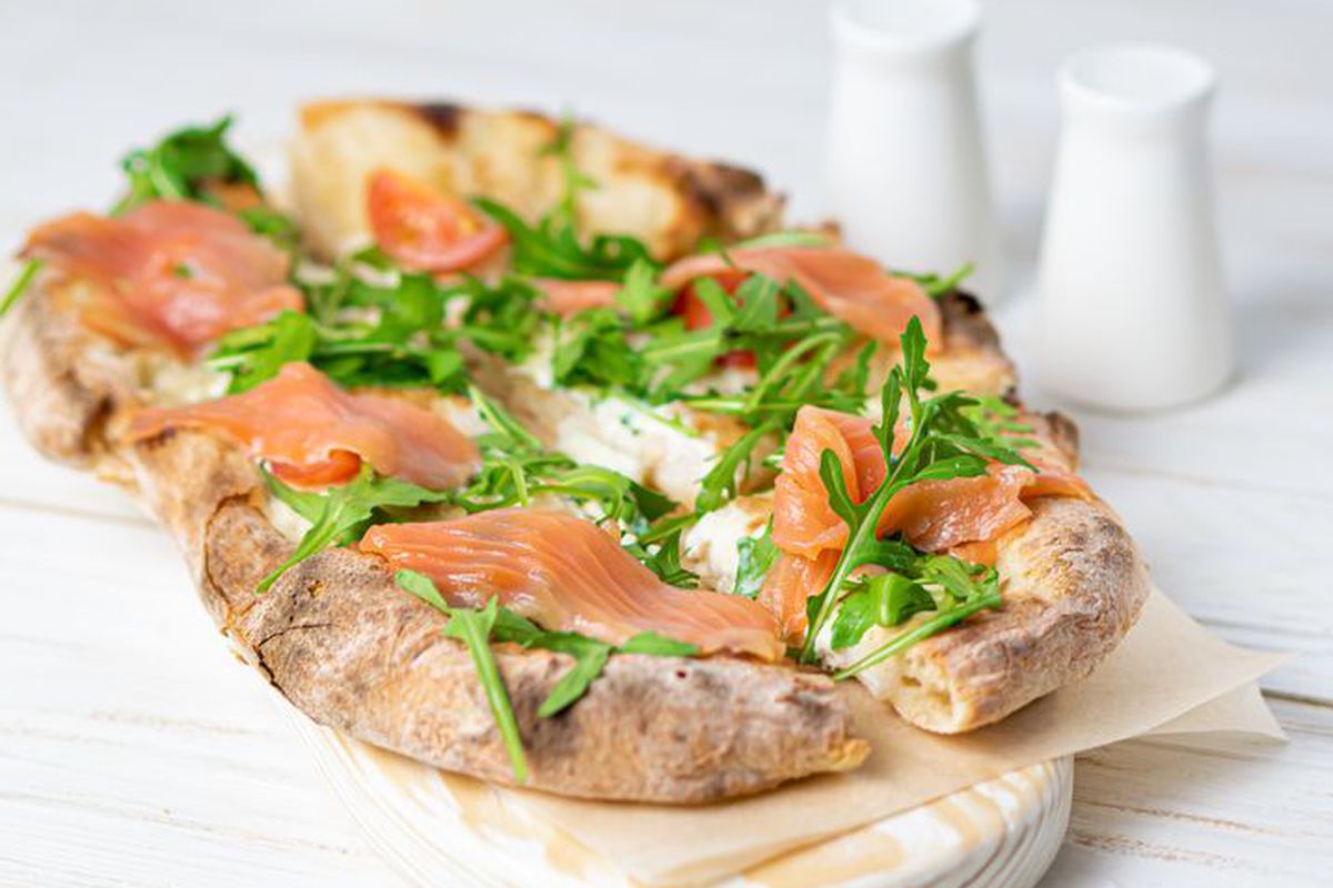 A flatbread topped with greens and smoked salmon. 