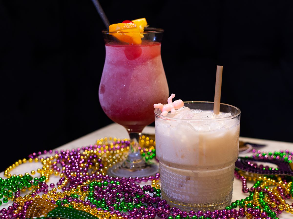 Two frozen cocktails sit on a table loaded with Mardi Gras beads. 