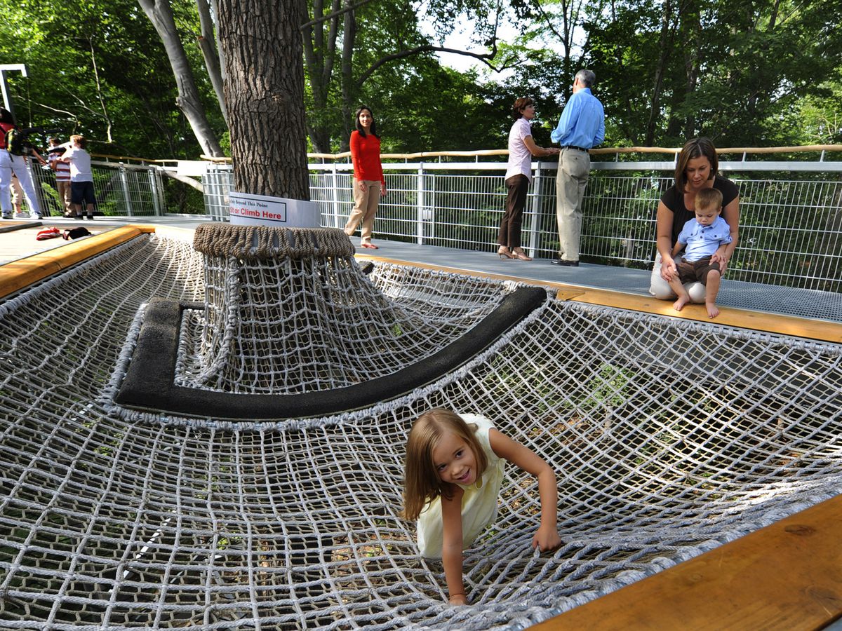 Children play in a playground in Philadelphia that has a net under a tree. 