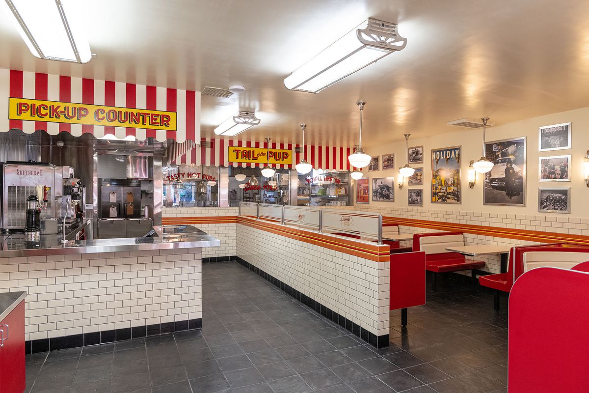 A red and white tiled interior of a throwback hot dog restaurant, with fluorescent lights.