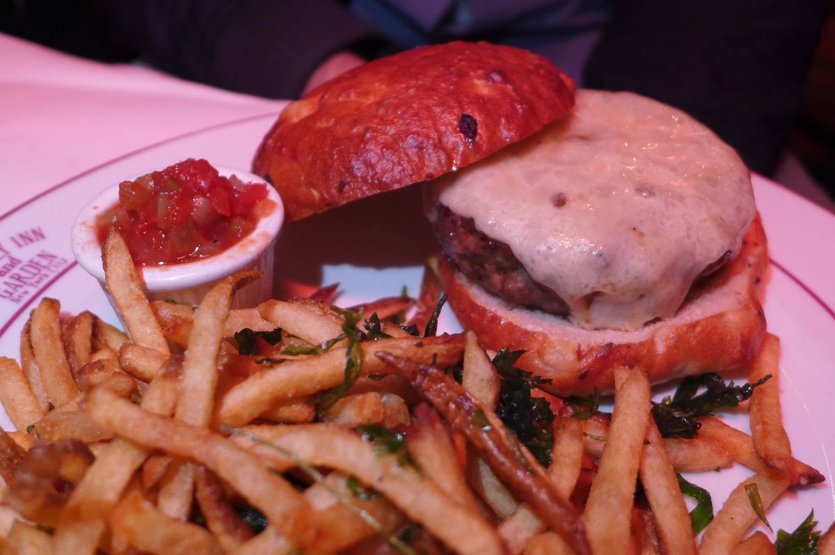 A cheeseburger in a bun with french fries in front.