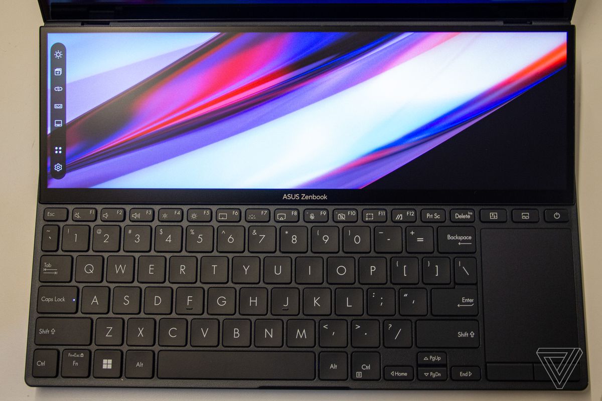 Das Tastaturdeck des Asus Zenbook Pro Duo 14 von oben gesehen.  Das ScreenPad zeigt einen mehrfarbigen Hintergrund mit einer Taskleiste auf der linken Seite an.