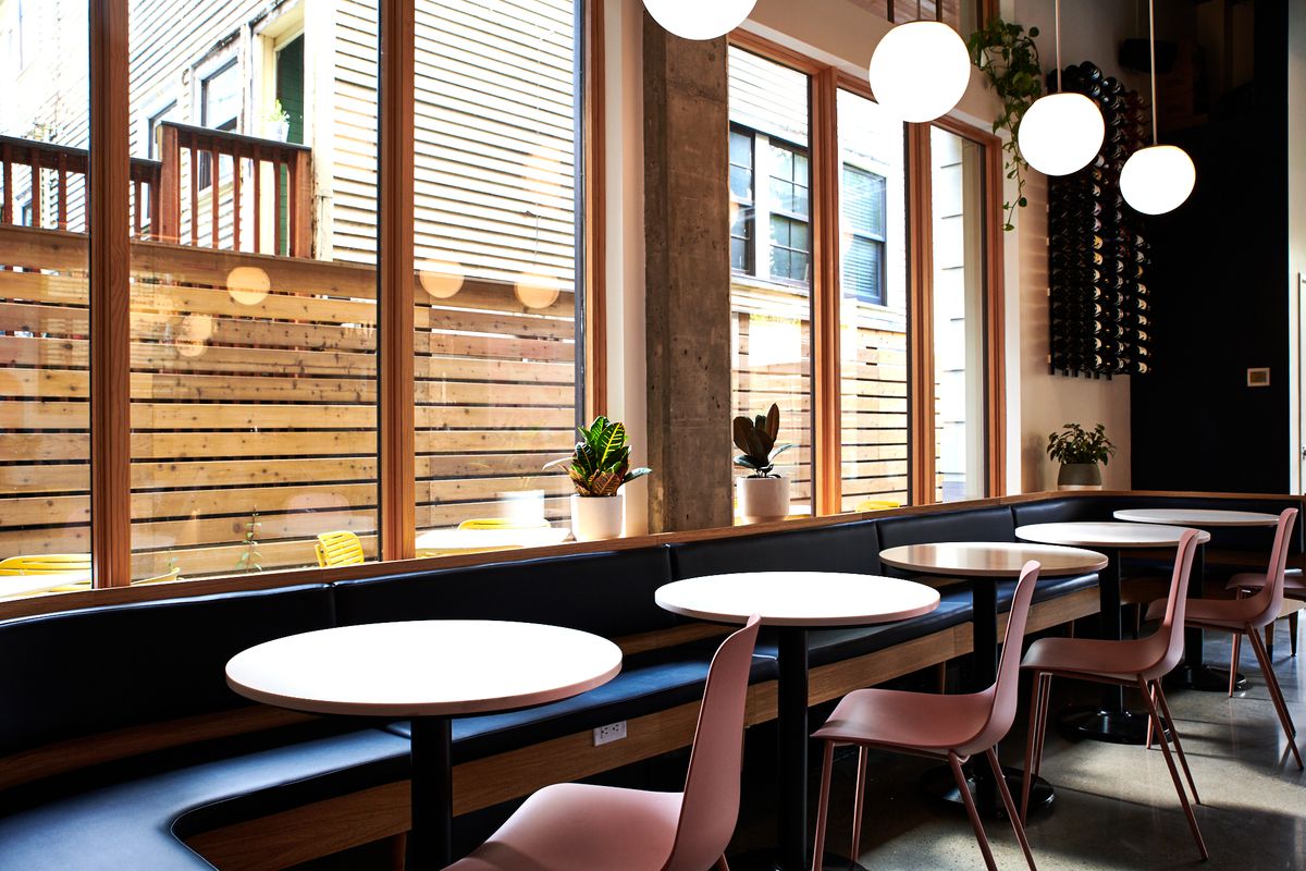 A picture of the pink-and-blue window seating at Bar Diane, lit by white globe lights