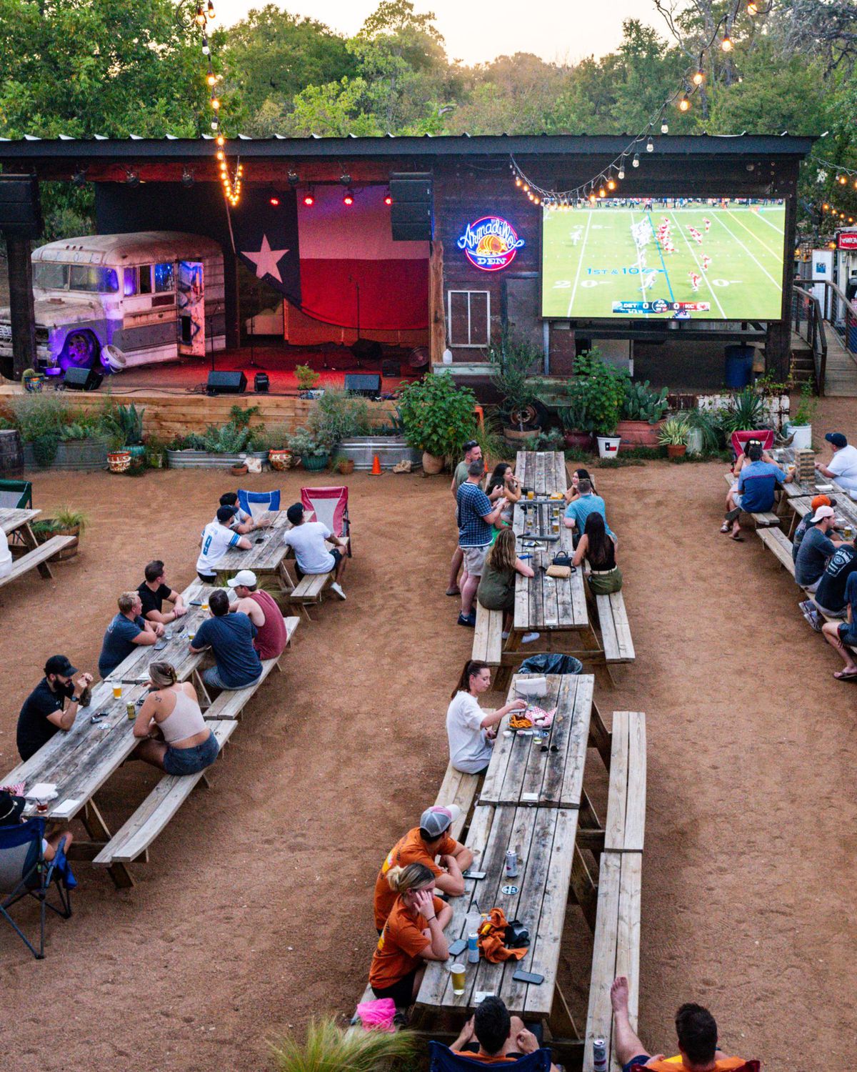 A restaurant patio with a screen showing a football game.