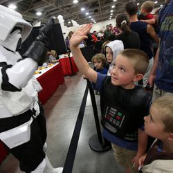 A Stormtrooper gives a high five to Harper Brace, as Darth Vader, at Comic Con at the Salt Palace Convention Center in Salt Lake City on Saturday, Sept. 7, 2013.