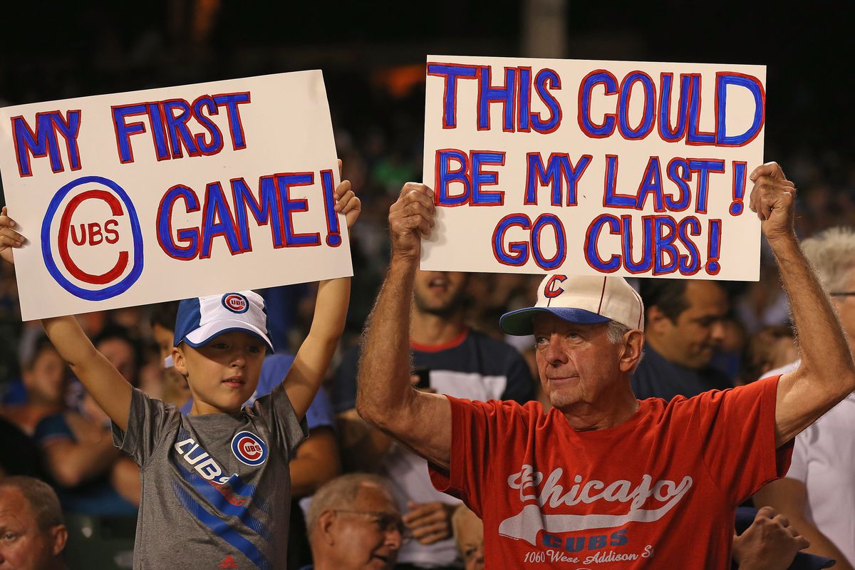 Jim Dolan of Aurora, Illinois and his grandson Andrew Naster hold signs as the Chicago Cubs take on the Milwaukee Brewers at Wrigley Field in Chicago, Illinois. (Photo by Jonathan Daniel/Getty Images)