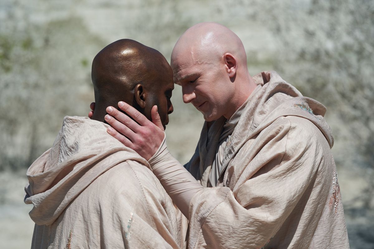 Two men (Kobna Holdbrook-Smith, Simon Harrison) touching foreheads in a still from His Dark Materials season 3