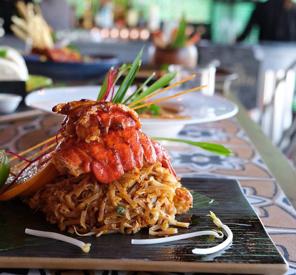 A pile of pad thai topped with large pieces of lobster