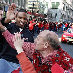 Utah coach Kyle Whittingham and quarterback Brian Johnson high-five Craig McQueen and his grandson as the University of Utah football players, coaches, band, cheerleaders and dignitaries are honored with a parade and pep rally in downtown Salt Lake City Friday. 