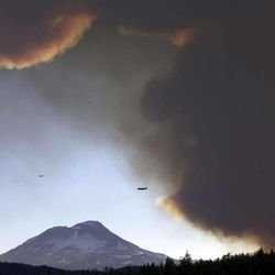 In this Sunday, Sept. 9, 2012 photo, a fire retardant and lead plane fly from the smoke plume in front of South Sister while fighting the Pole Creek fire, southwest of Sisters, Ore. 