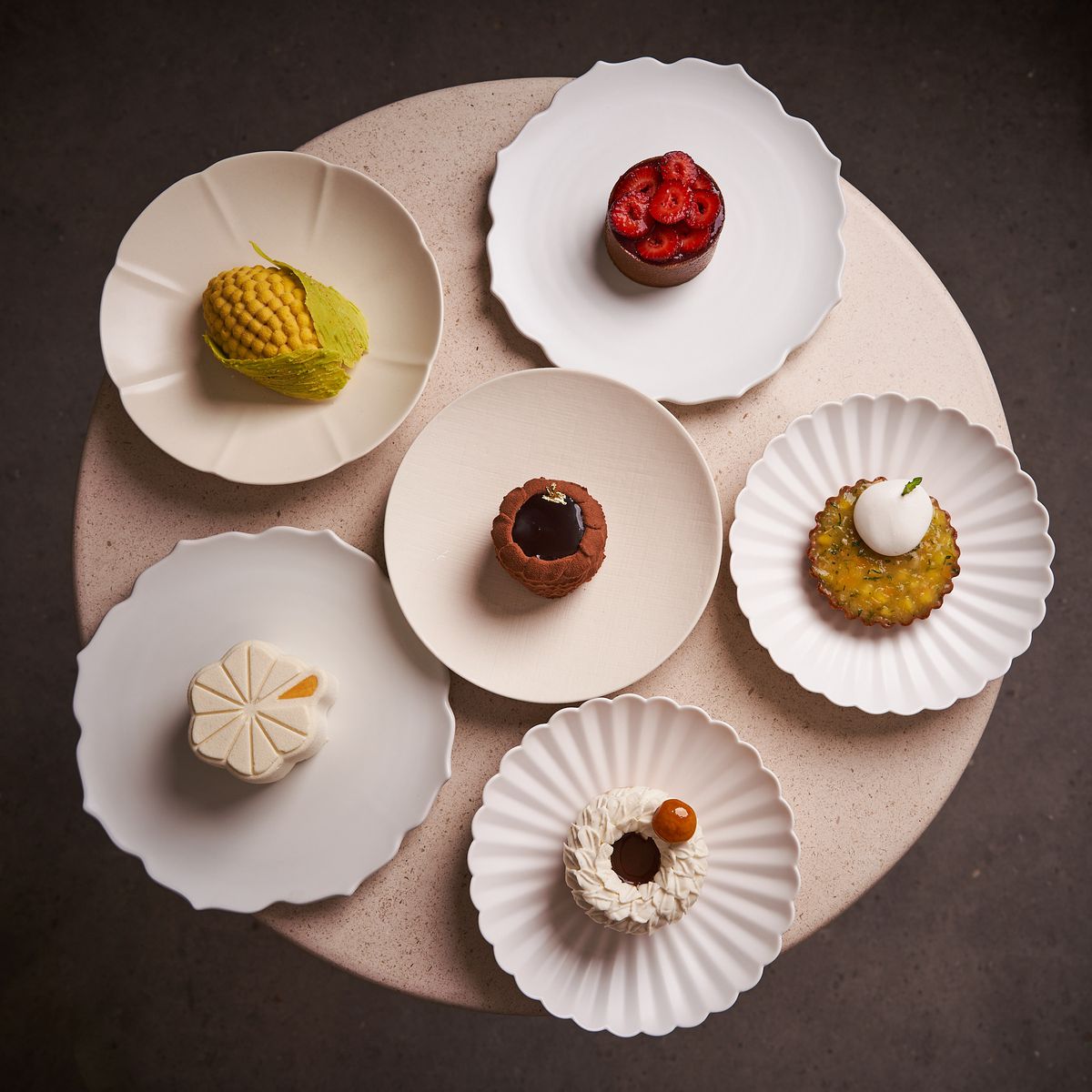 A round white table with bowls featuring six of Lee’s pastries in varying colors.