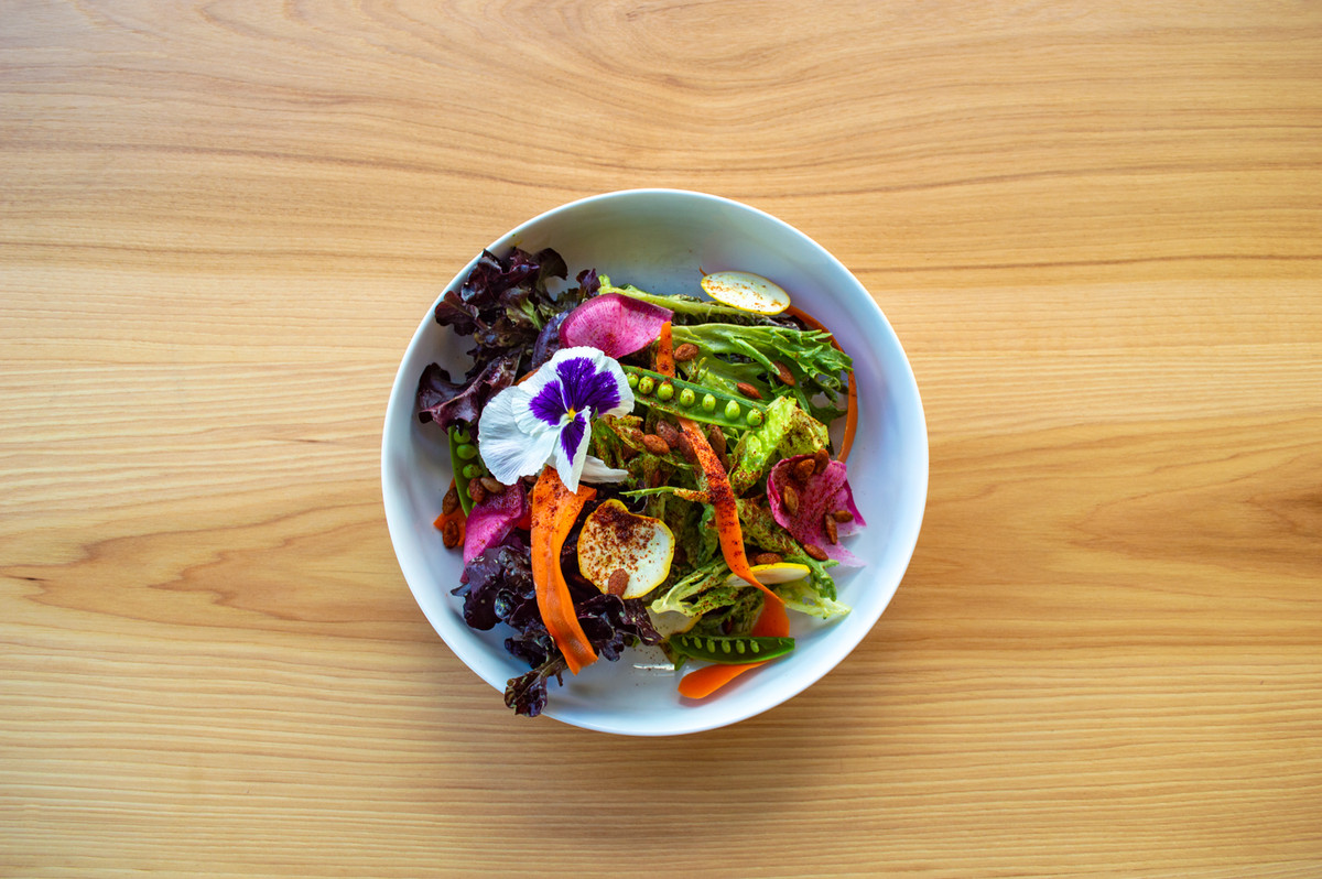 An overhead shot of a plate of salad with fresh vegetables and lots of colorful flowers.