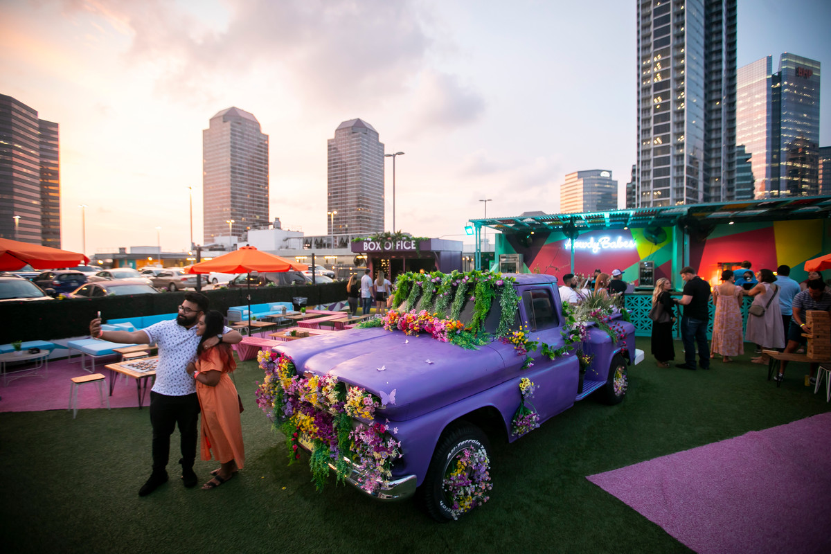 A couple taking a selfie in front of a painted truck covered in flowers in the lounge at Rooftop Cinema Club.