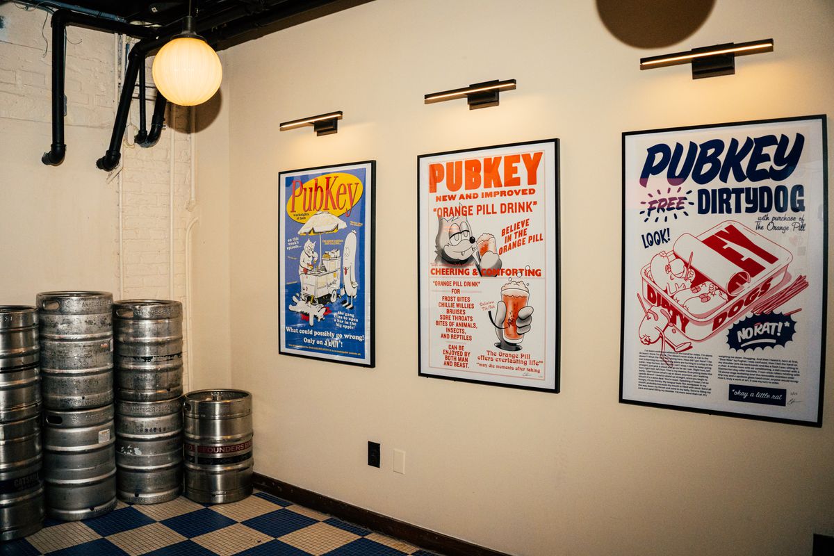 Signs for a restaurant, called Pubkey, hang in the back of a bar with tiled floors.