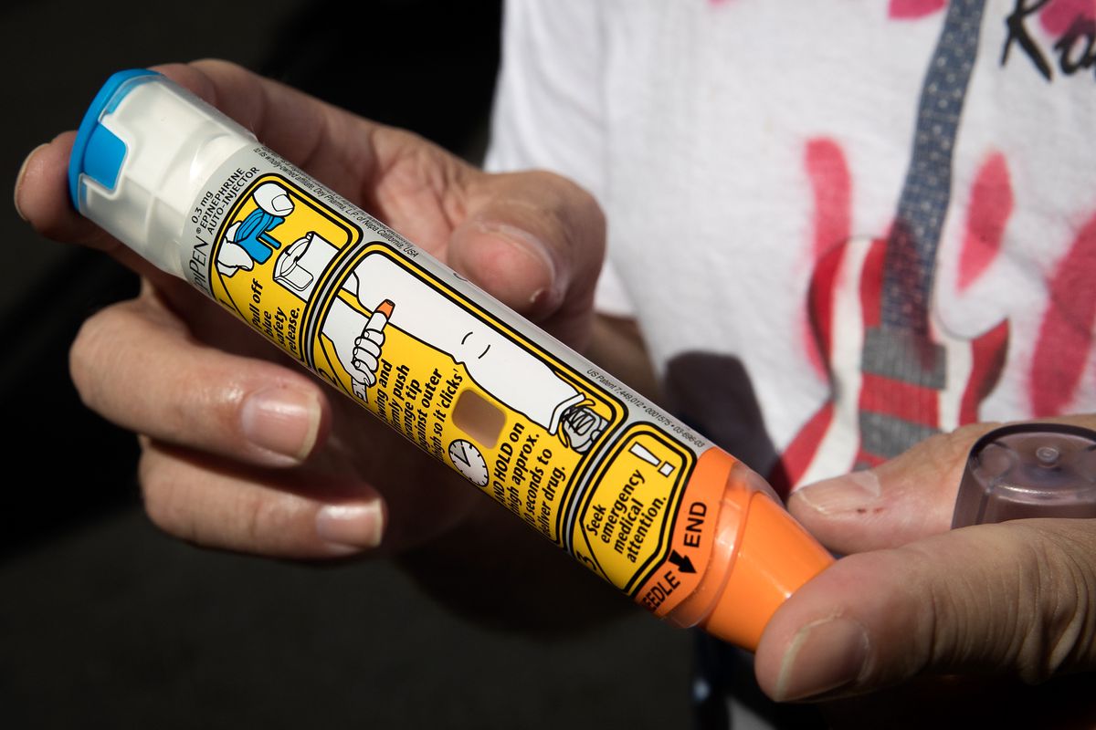 A person holds an EpiPen.