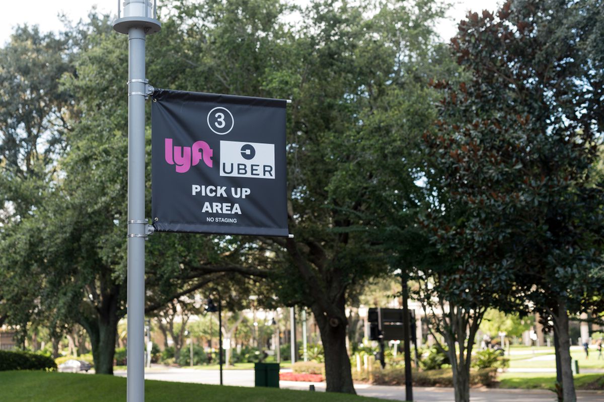 A banner indicating a Lyft and Uber pick-up area on a street.