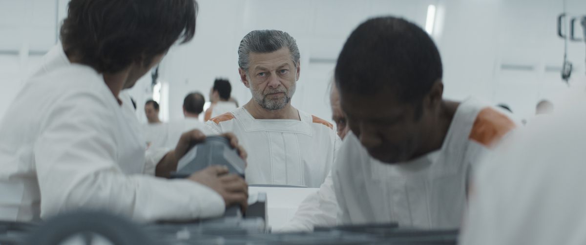 Andy Serkis looks on as Cassian Andor and Jemboo put together a piece of equipment in Andor.