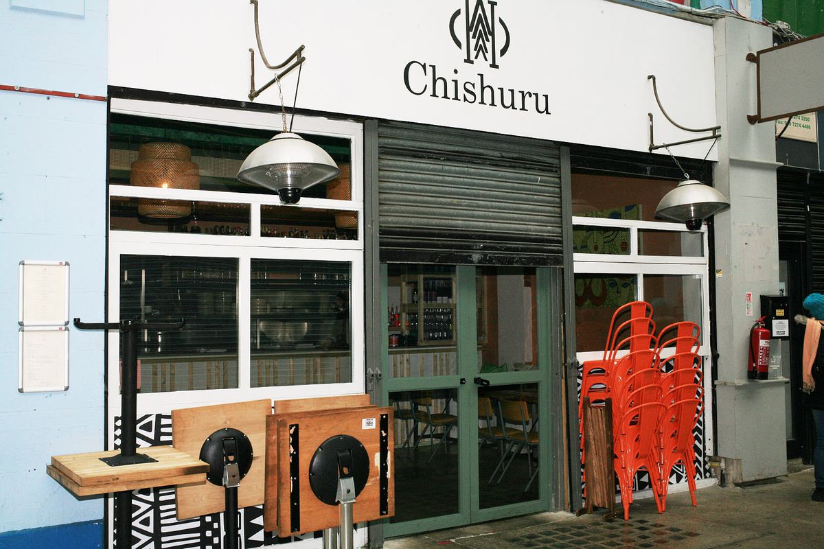 The exterior of Chishuru restaurant in Brixton Market, shutters halfway up. The name is written above in black, on a beige background