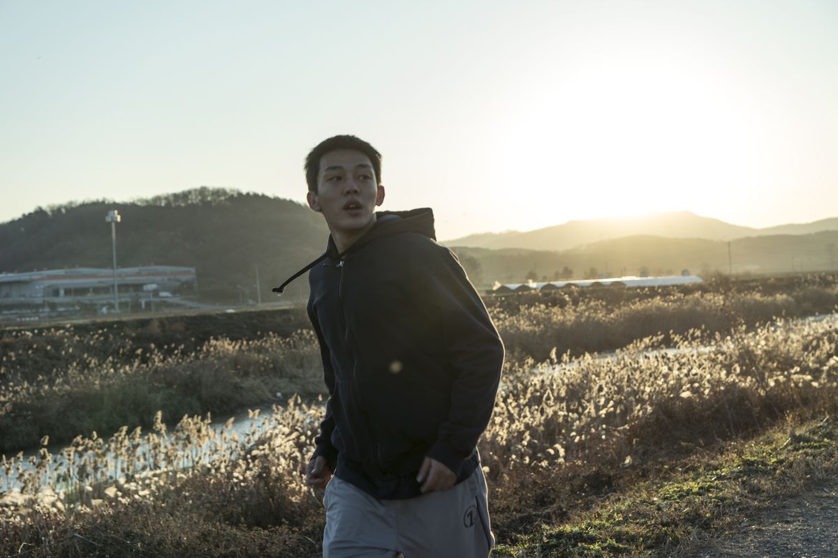 Jong-su (Yoo Ah-in) wanders through a field.